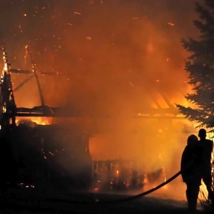 House in fire at night. Firefighters fighting with fire.