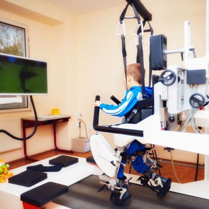 young boy passes robotic gait therapy in rehabilitation center
